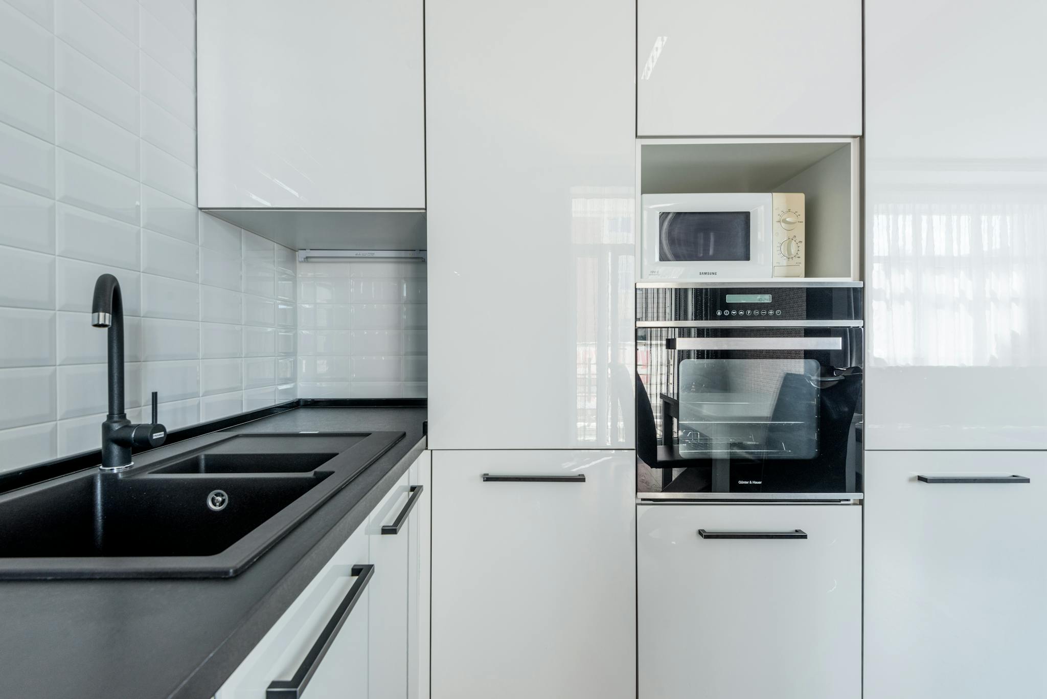 Sleek and modern white kitchen with integrated appliances and minimalist design.